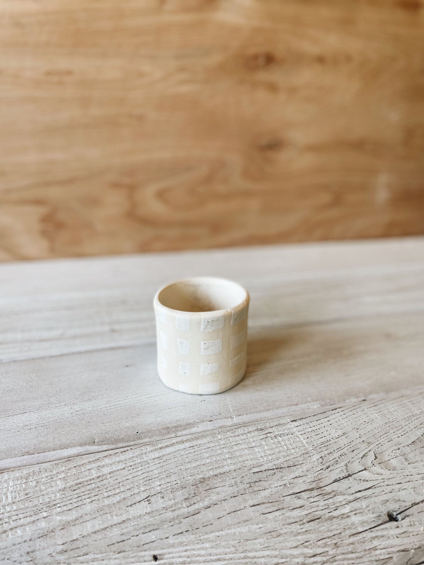 Checkered ceramic cup on wood background.