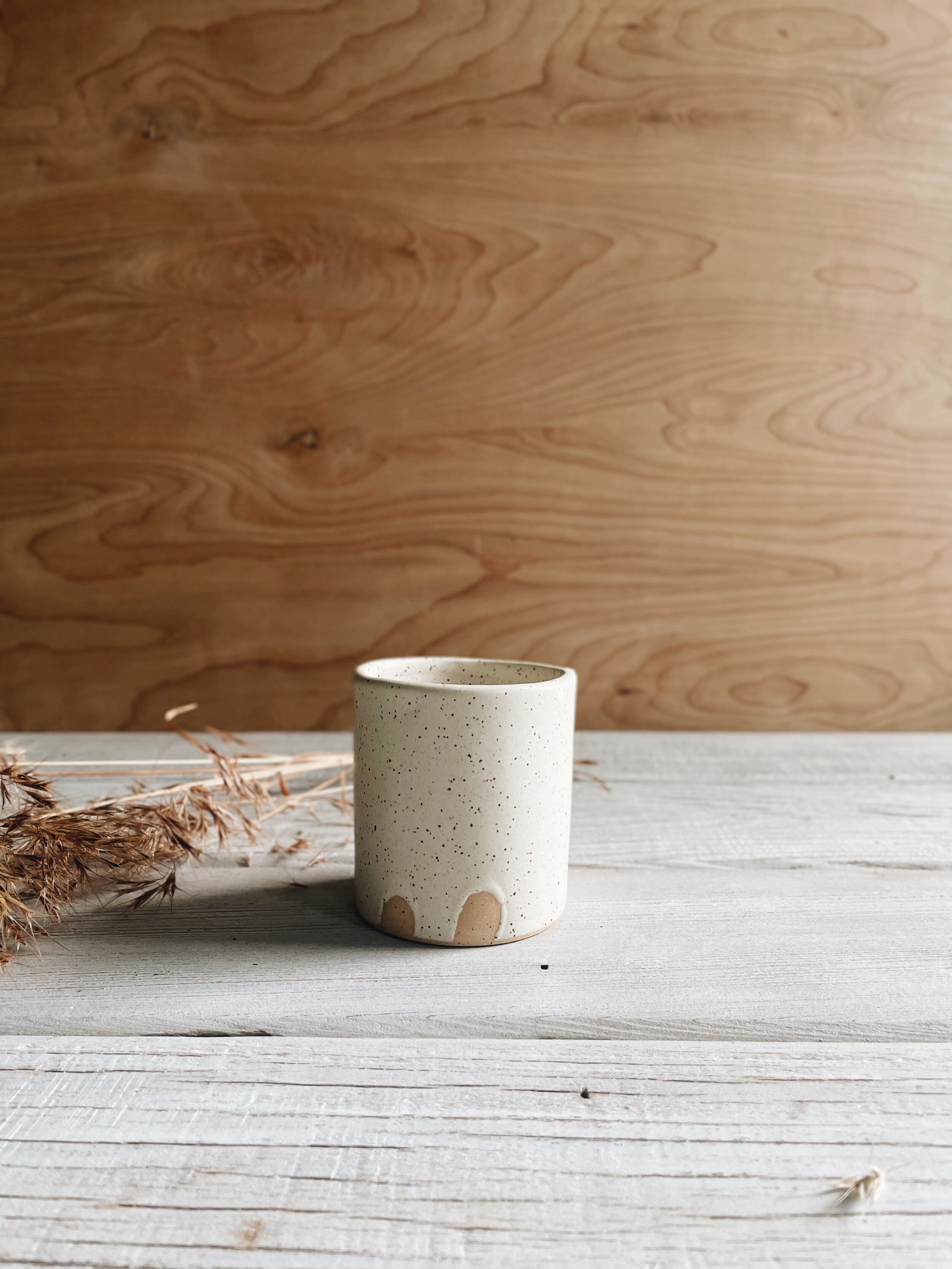 Speckled ceramic cup on wood background