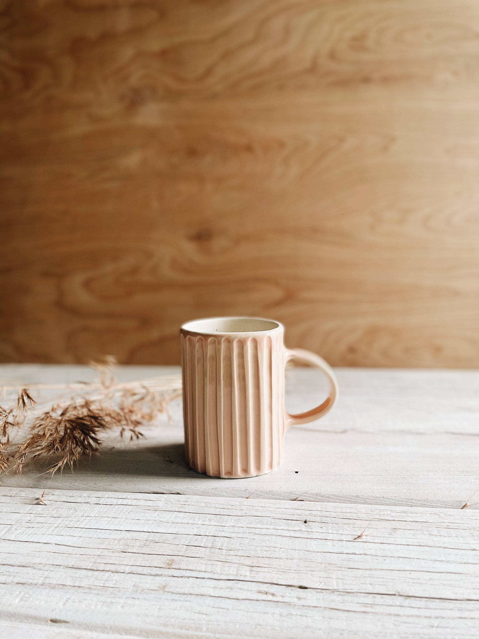 Ceramic lined mug in blush on wood background.