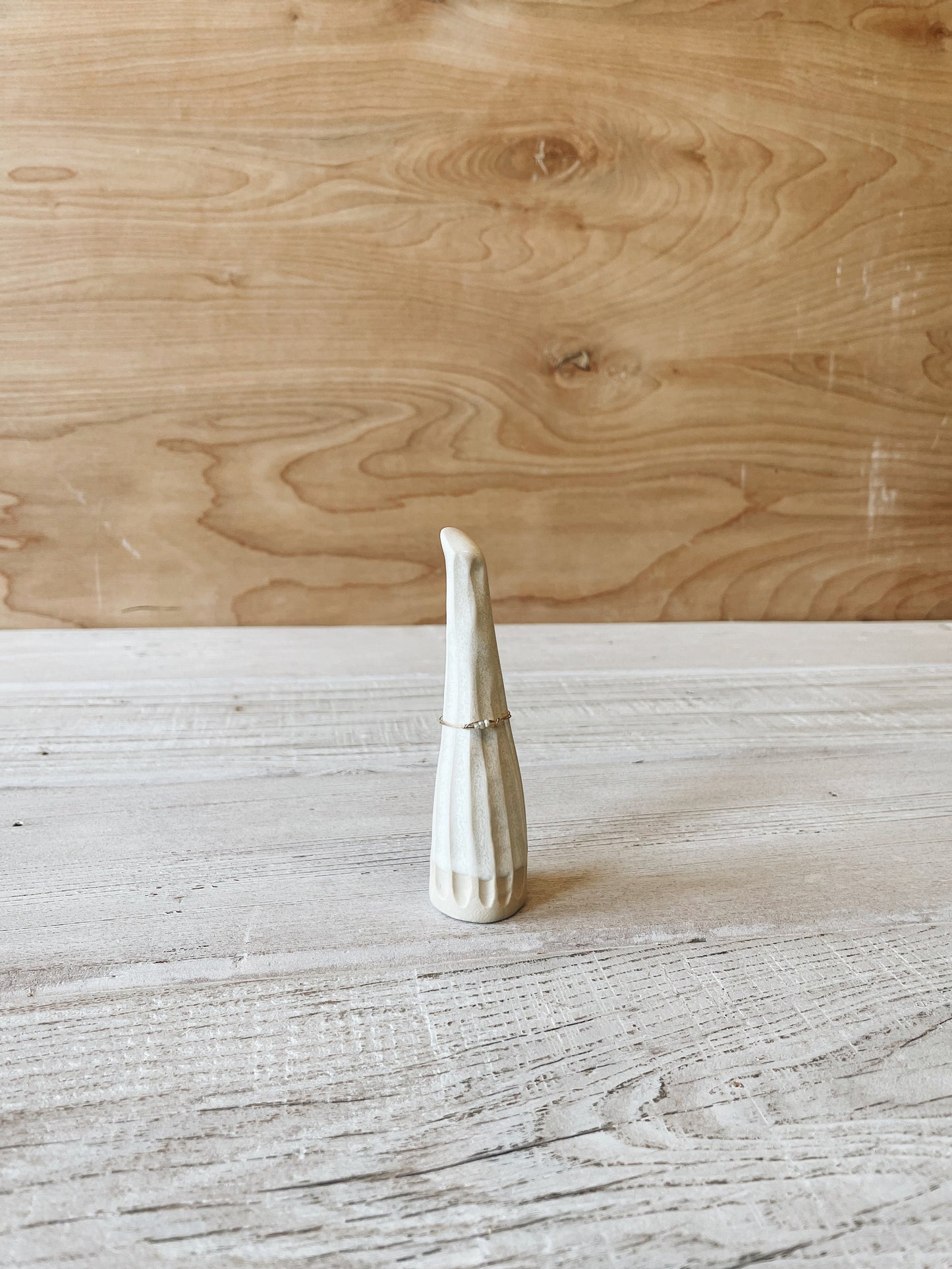 Matte white carved ceramic ring cone with ring on it.
