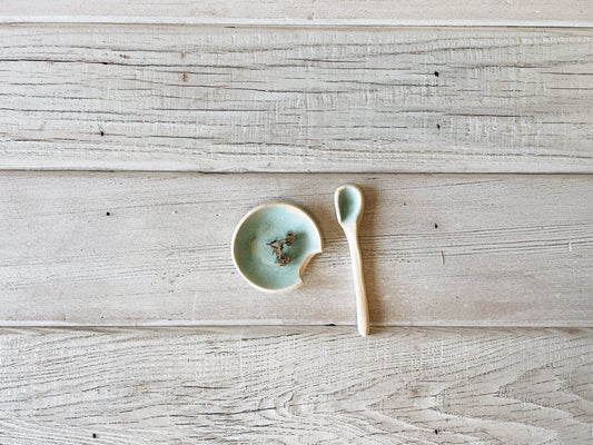 Ceramic salt dish  & spoon set on wooden table. 