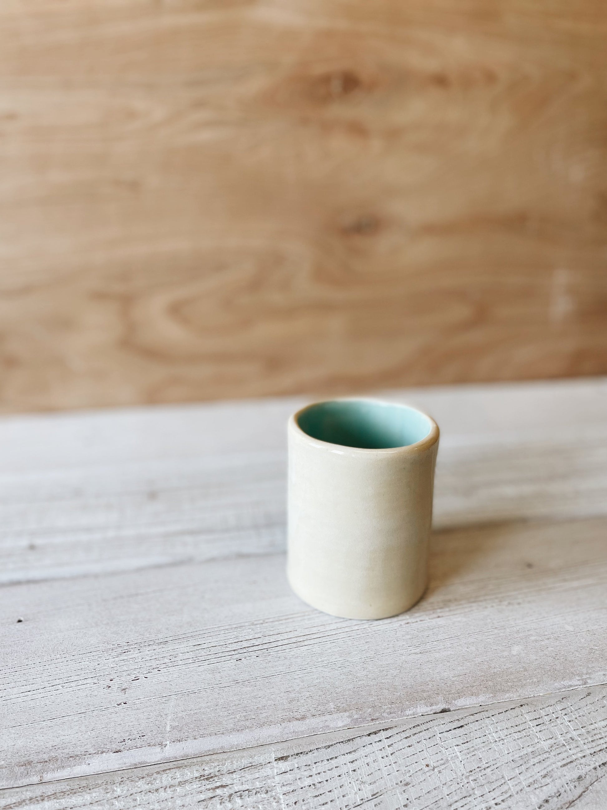Small ceramic cup on wooden table.