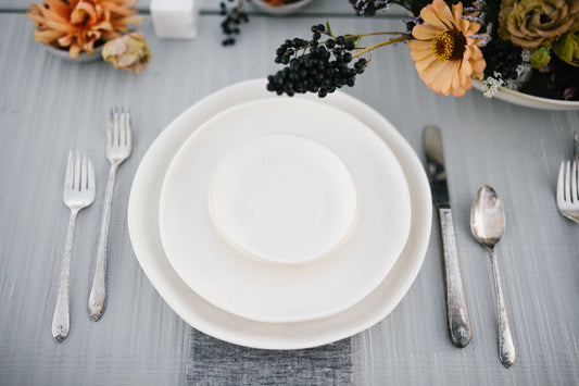 White matte ceramic dinner dish set with silverware on the side. 